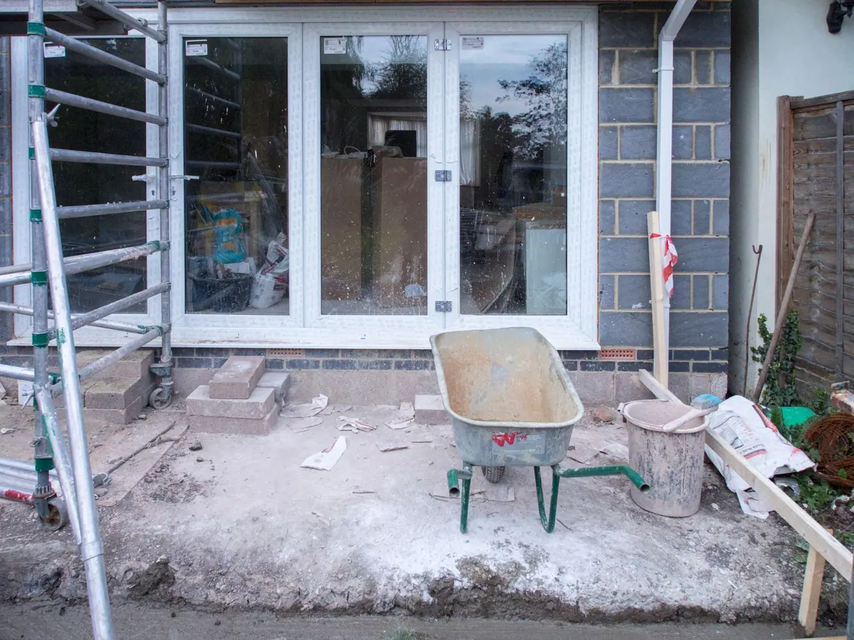 Chantier d’extension de maison avec échafaudage et brouette Chantier d’extension de maison avec échafaudage et brouette