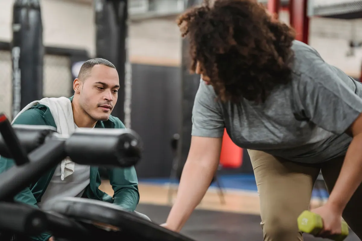 Coach sportif accompagnant une cliente pendant sa séance