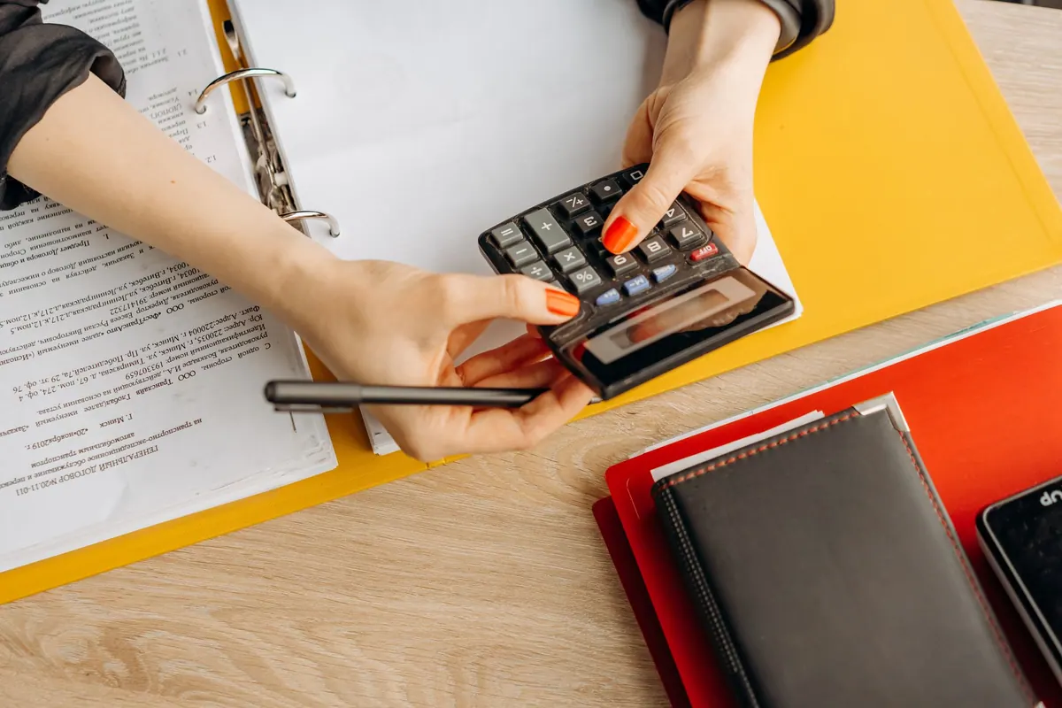 Comptable utilisant une calculatrice devant un classeur