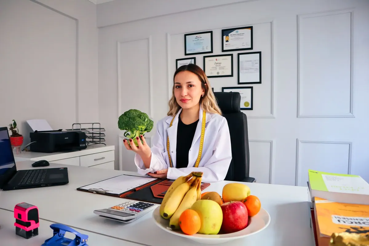 Diététicienne à son bureau, fruits et légumes devant elle