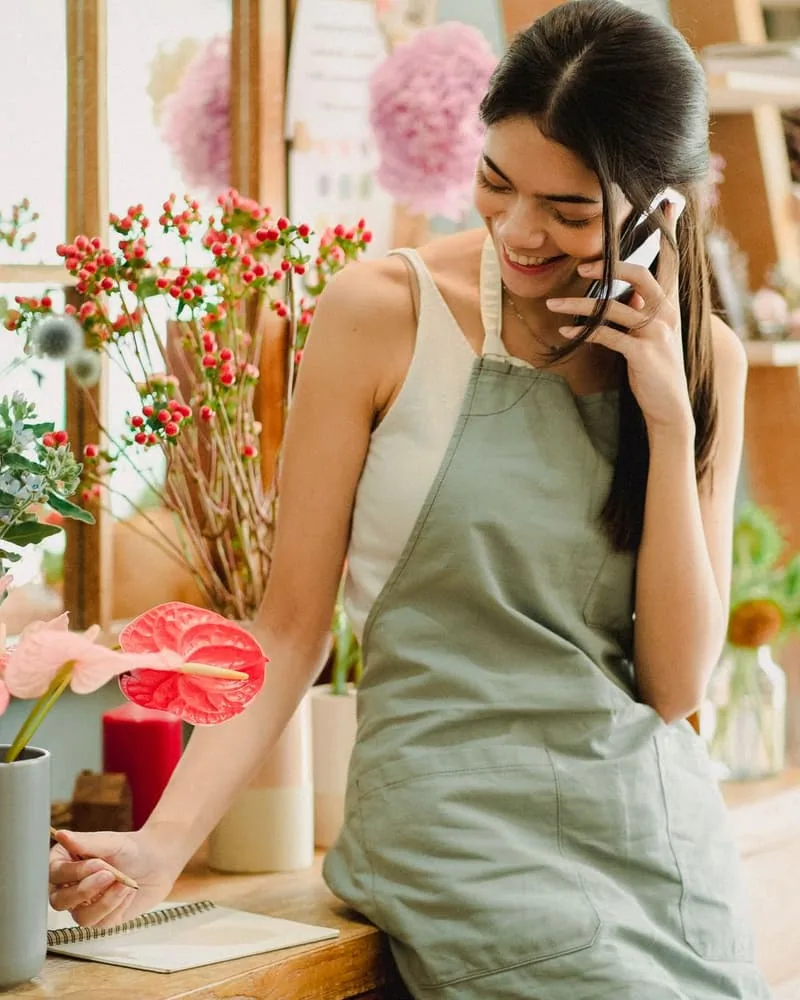 Fleuriste au téléphone avec un client dans sa boutique (Commerce)