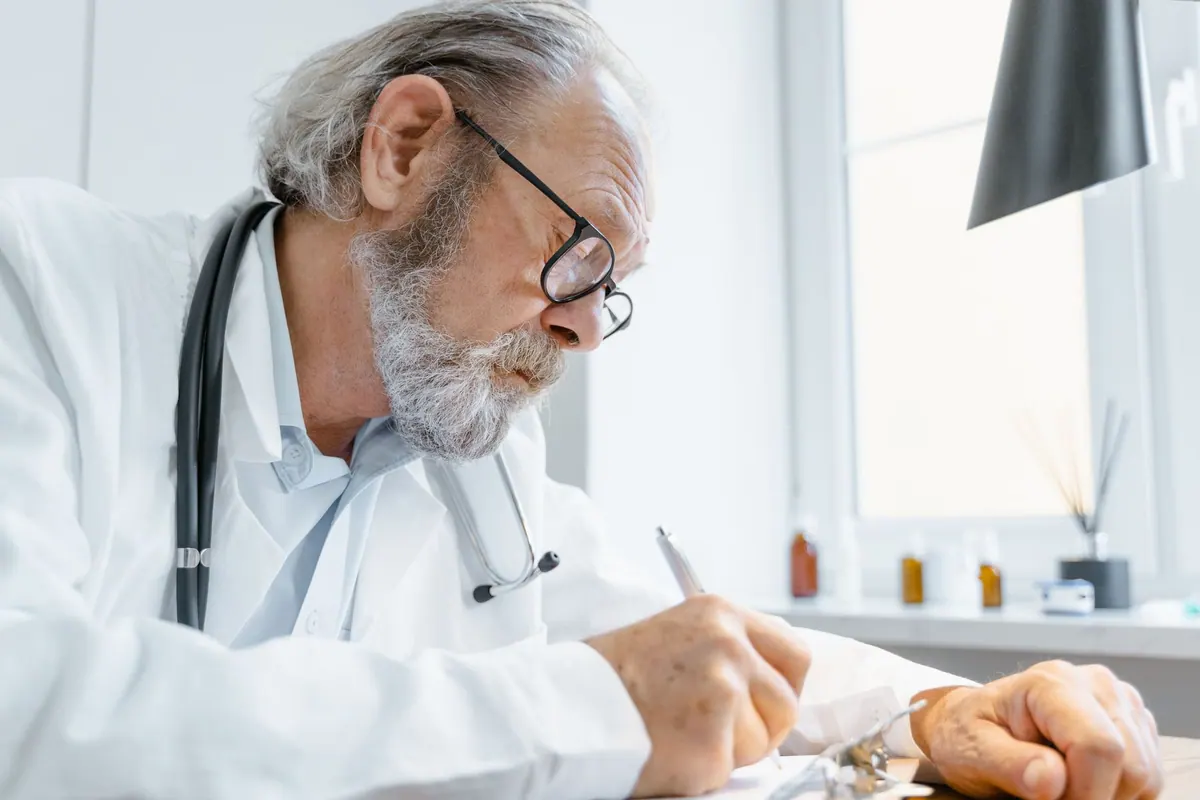 Médecin rédigeant des notes dans son cabinet Médecin rédigeant des notes dans son cabinet