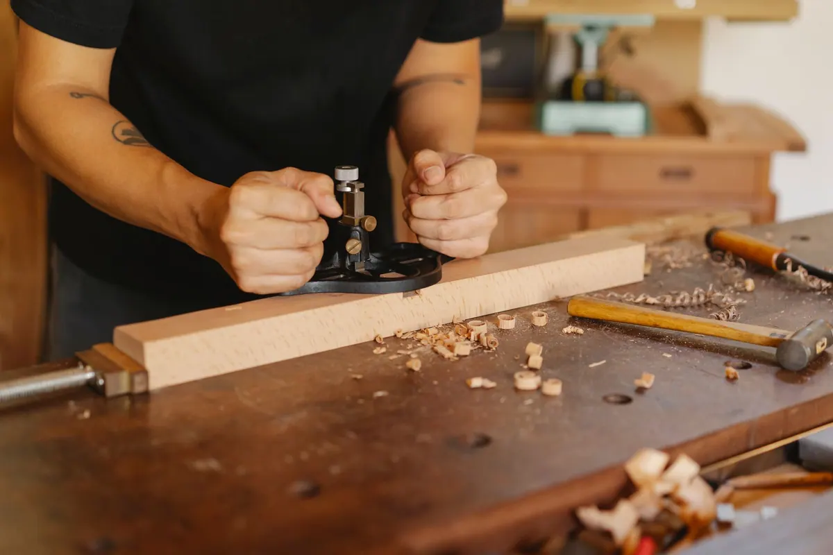 Menuisier travaillant une pièce de bois au rabot sur l’établi Menuisier travaillant une pièce de bois au rabot sur l’établi