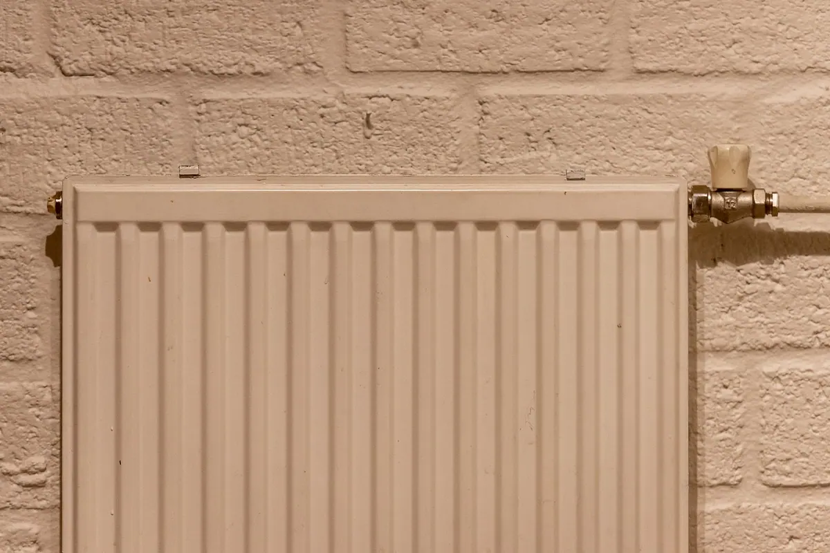 Radiateur avec robinet de réglage contre un mur de briques Radiateur avec robinet de réglage contre un mur de briques