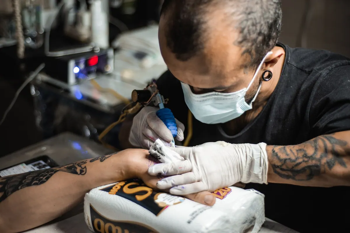 Tatoueur en séance, gants et masque Tatoueur en séance, gants et masque